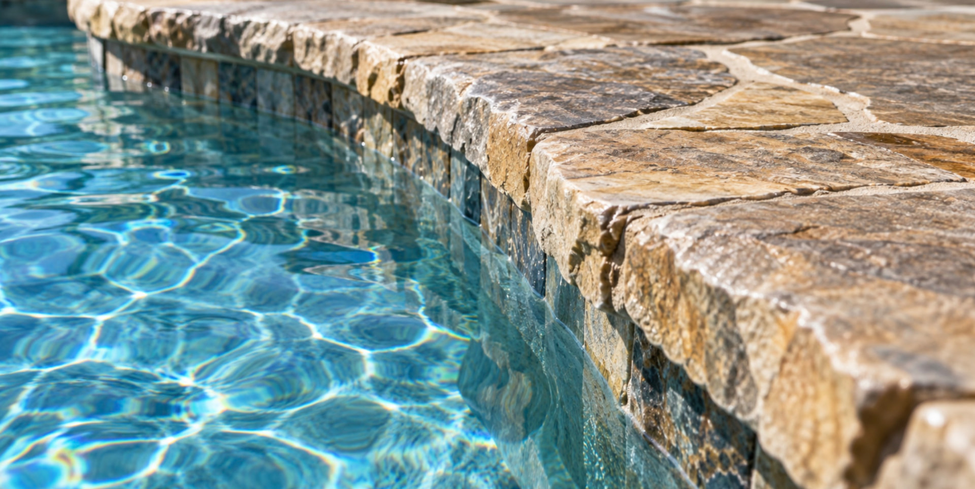 Natural stone pool coping above a tiled waterline